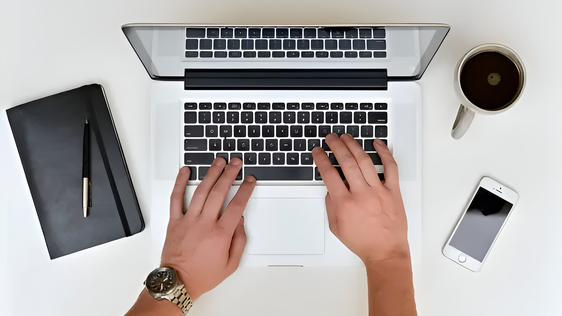 Hands typing on laptop with coffee nearby.