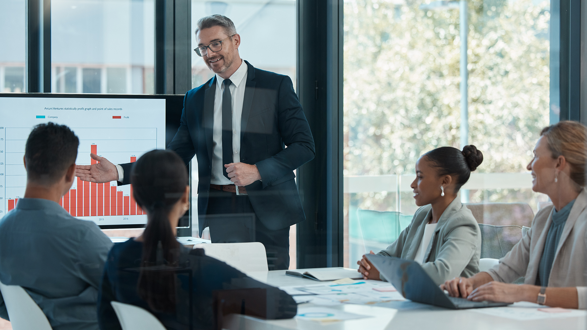 Business presentation with colleagues and graph display.