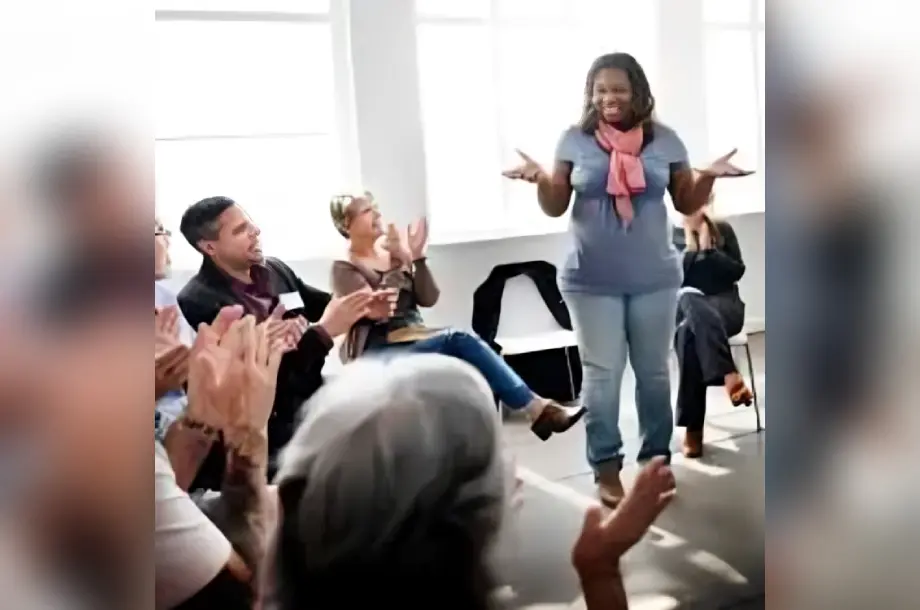 People applauding a woman standing and speaking.