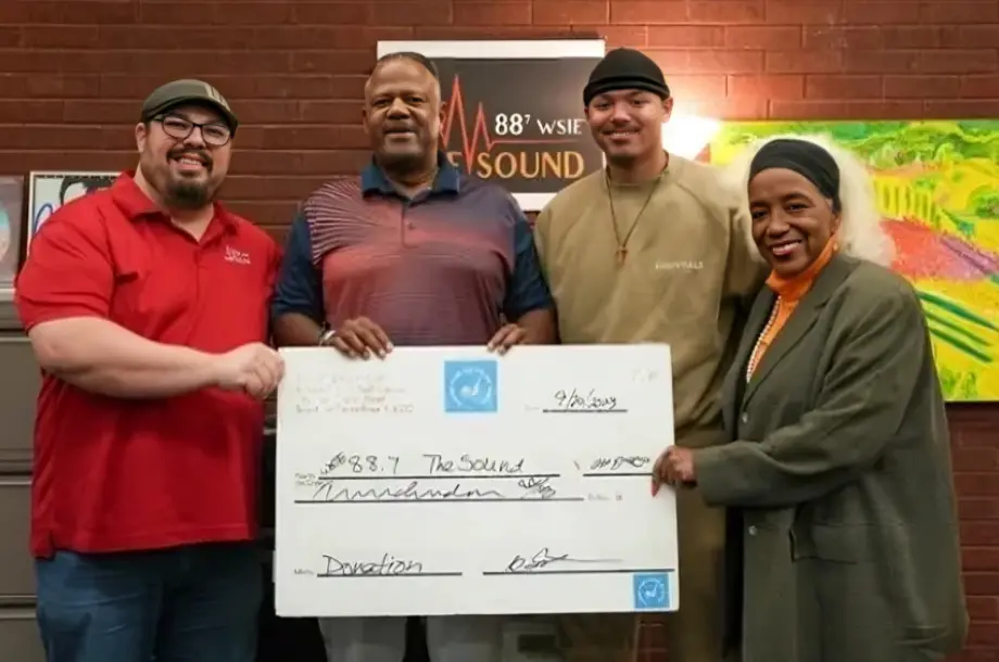 Four people holding a large donation check.