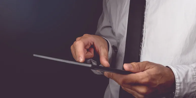 Man using tablet in formal attire.